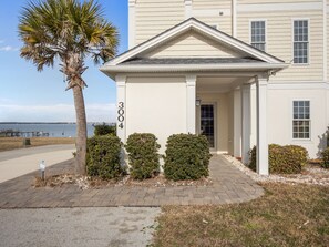 A two-story building with a white facade, a number '3004' on the side, and a covered entrance with columns. - Soundfront Living with Ocean Views, Private Dock & Pool (Emerald Isle)