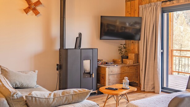 Een gezellige woonkamer met een bank, een salontafel en een aan de muur bevestigde televisie.