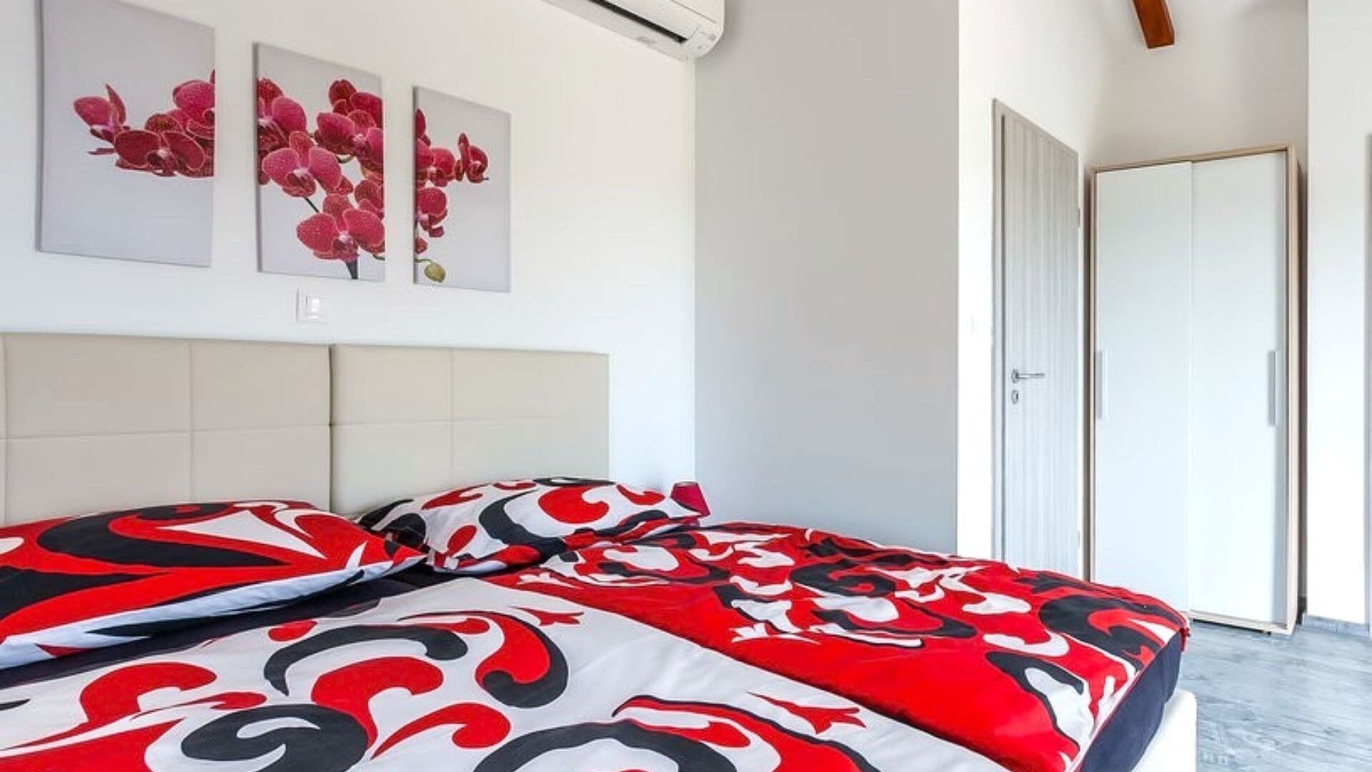A bedroom with a bed, a door, and three wall-mounted artworks.