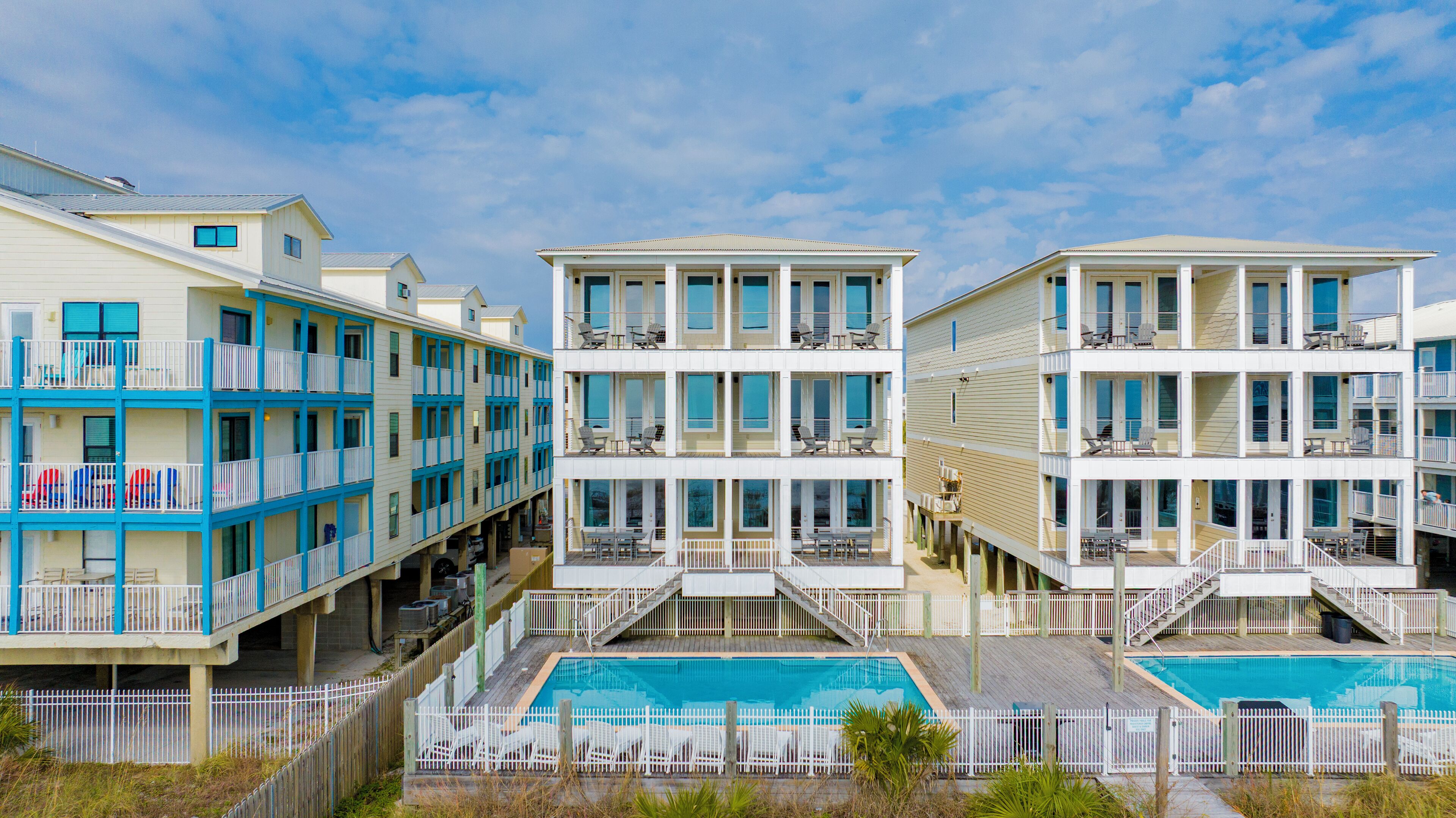 A beachfront hotel with multiple balconies, a swimming pool, and a wooden deck area.