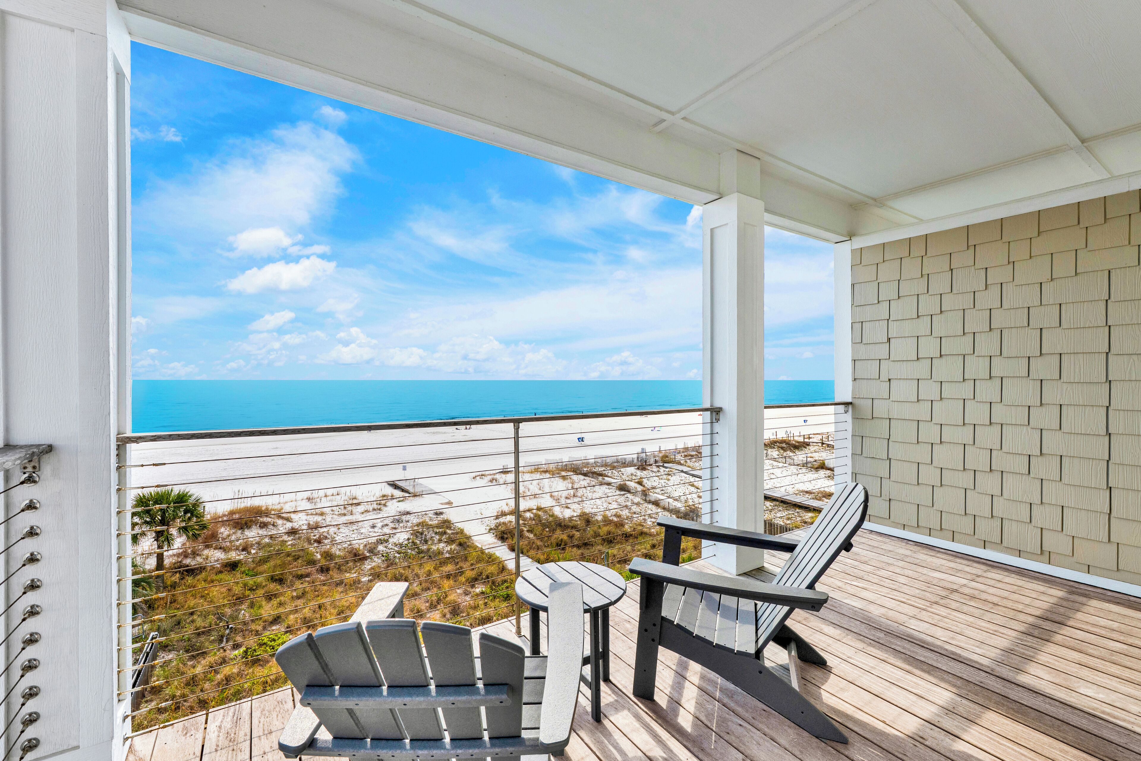 A balcony with a view of the beach and ocean.