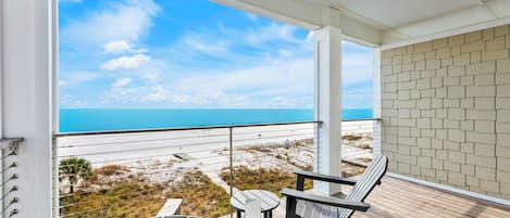 A balcony with a view of the beach and ocean.
