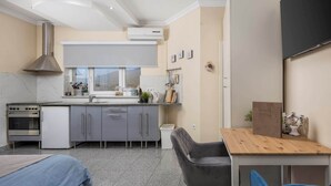 Cocina compacta con estufa, horno y muebles de cocina modernos. Cuenta con una zona de comedor con mesa y sillas de madera.