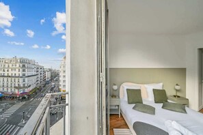 A hotel room with a bed, nightstands, and a view of a city street. - Close to Paris City Center | Eiffel Tower View (Paris)