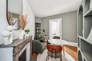 Ein modernes Wohnzimmer mit Kamin, Esstisch und einem großen Spiegel.