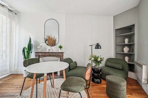 A modern living room with a round table, green sofas, a fireplace, and a bookshelf. - Close to Paris City Center | Eiffel Tower View (Paris)