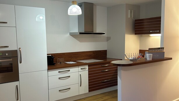 Een moderne keuken met witte kastjes, een houten aanrechtblad en een ingebouwde kookplaat.