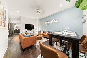 A modern living room with a dining area, a sofa, a coffee table, and a TV.