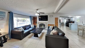 Een moderne woonkamer met een bank, salontafel en een open haard. Achtergrond is een keuken.