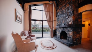 A living room with a stone fireplace, two armchairs, a large window with curtains, and a view of the outdoors. - MONK BY THE LAKE SAPANCA (Sapanca)