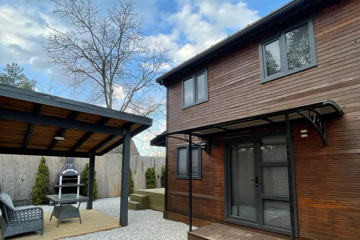 Una casa moderna con un patio, zona de barbacoa y espacio de estar cubierto.