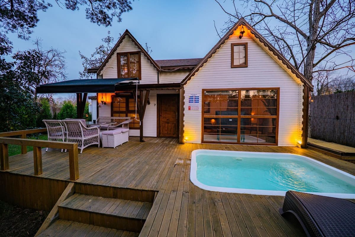 Una casa con jacuzzi, mobiliario exterior y un porche cubierto.