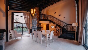 A spacious living area with a dining table, chairs, a fireplace, a staircase, and a view through large windows. - MONK BY THE LAKE SAPANCA (Sapanca)