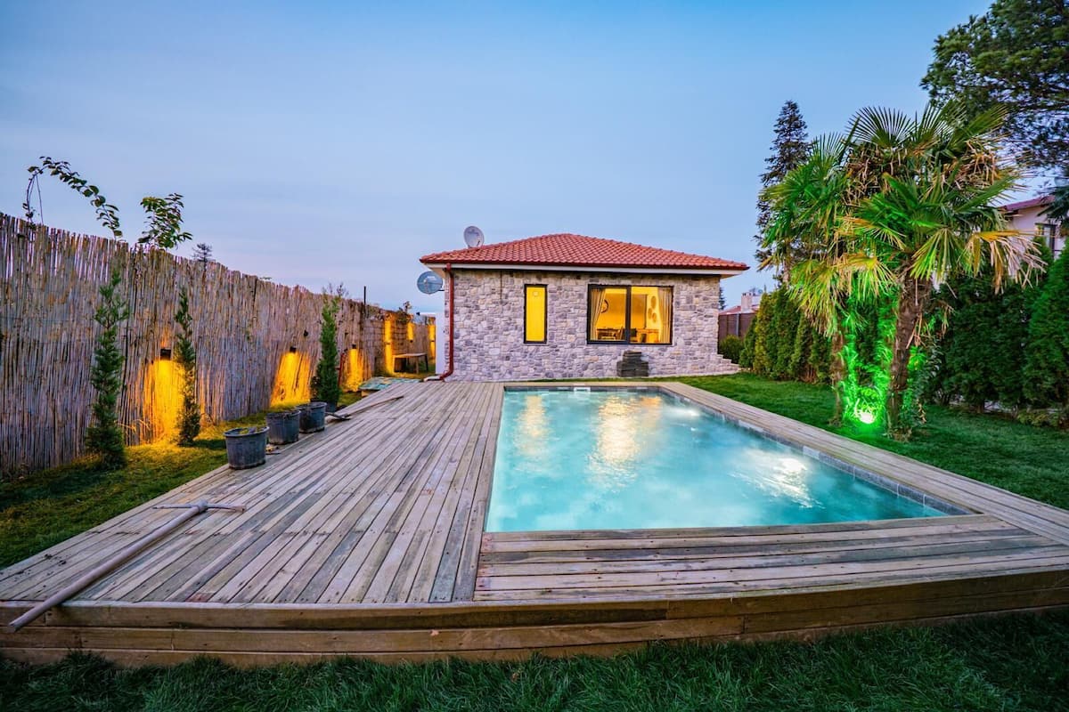 Una casa con piscina, terraza de madera y antena parabólica.