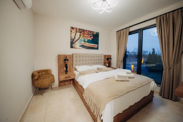 A bedroom with a large bed, a nightstand, a fluffy chair, a painting, and a view of the outdoors. - MONK BY THE LAKE SAPANCA (Sapanca)