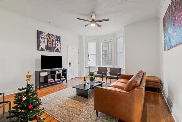 Una sala de estar con televisor, sofá, mesa de centro y árbol de Navidad.