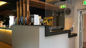 Un comptoir d’accueil avec un panneau indiquant la disponibilité du Wi-Fi, une horloge et une carte du monde affichée au mur.