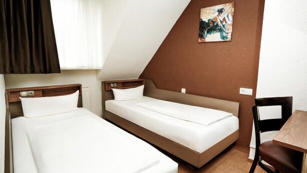 Een kamer met twee bedden, een houten tafel en een stoel.
