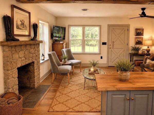A cozy room with a stone fireplace, two armchairs, a television, and a large window.