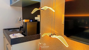 A modern bathroom with a coffee machine, a towel dispenser, and a unique light fixture. - Studio Vista Mar Lateral 1 - By Almare (João Pessoa)