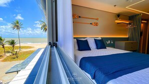 A hotel room with a large bed, a view of the beach, and two wooden paddles on the wall. - Studio Vista Mar Lateral 1 - By Almare (João Pessoa)