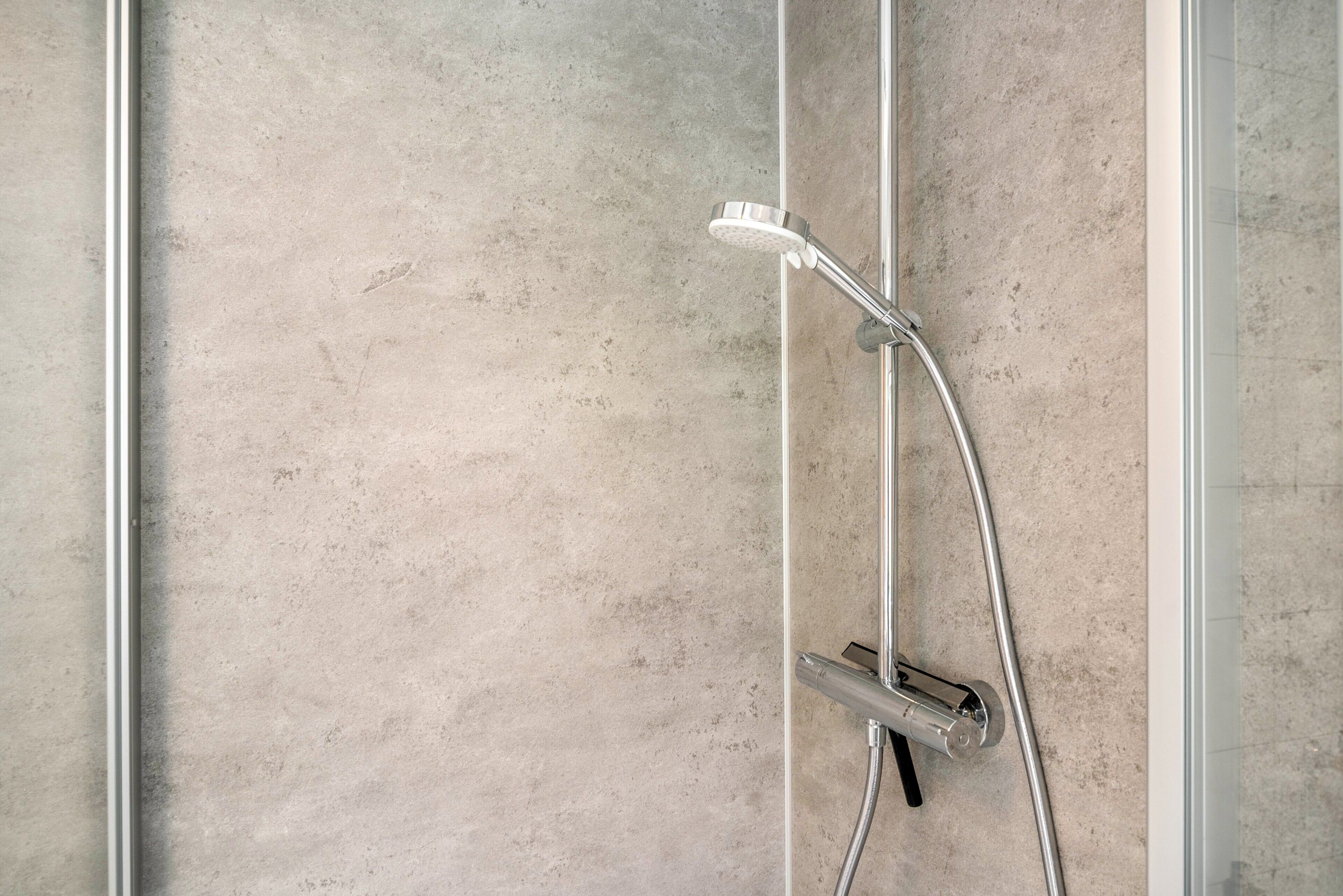 A shower with a handheld showerhead and a wall-mounted control valve.