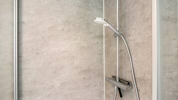 A shower with a handheld showerhead and a wall-mounted control valve.
