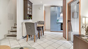 Une cuisine moderne dotée d’un four encastré, un coin repas avec une table ronde et des chaises, et un escalier menant à l’étage supérieur.