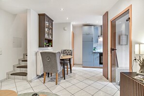 Une cuisine moderne dotée d’un four encastré, un coin repas avec une table ronde et des chaises, et un escalier menant à l’étage supérieur.