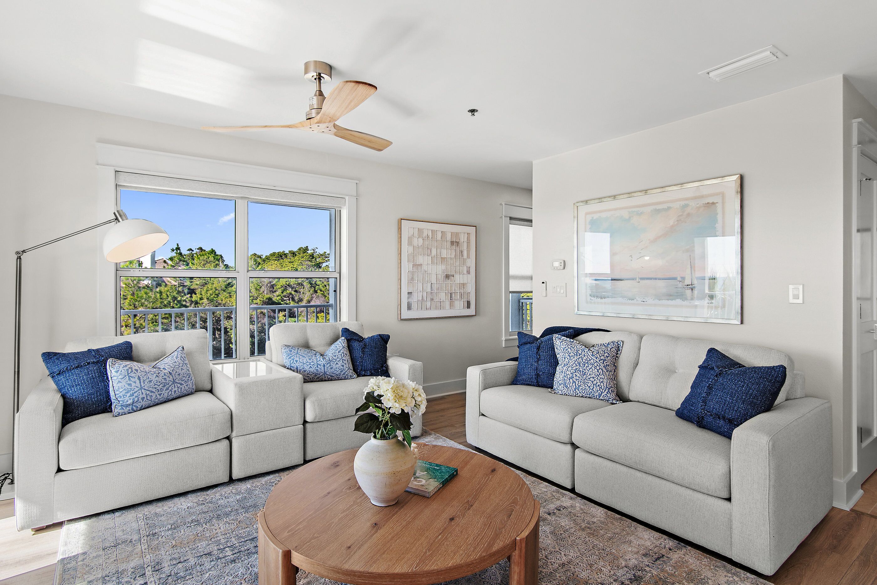 A modern living room with two sofas, a coffee table, and a ceiling fan.