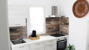 Eine moderne Küche mit Einbauherd, Spüle und Backofen, ausgestattet mit hellem Holzkorpus und einem großen Fenster.