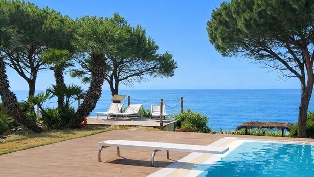 A swimming pool with a view of the sea, surrounded by trees and lounge chairs. - Villa Alisea in Cefalù, garden, pool and sea (Cefalù)