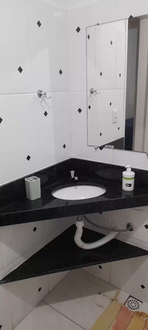 A bathroom with a black countertop, white sink, and a mirror above it. - Studio apartment 301, beach within walking distance. (Anchieta)
