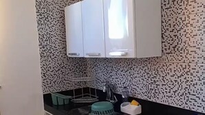 Een keuken met witte kasten, een zwart aanrecht en een achterwand met een patroon.