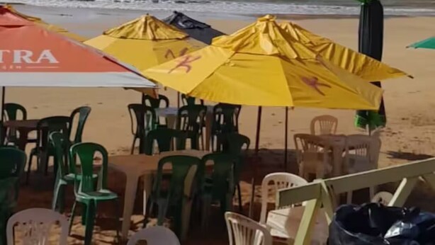 Een restaurant aan het strand met terras en parasols.