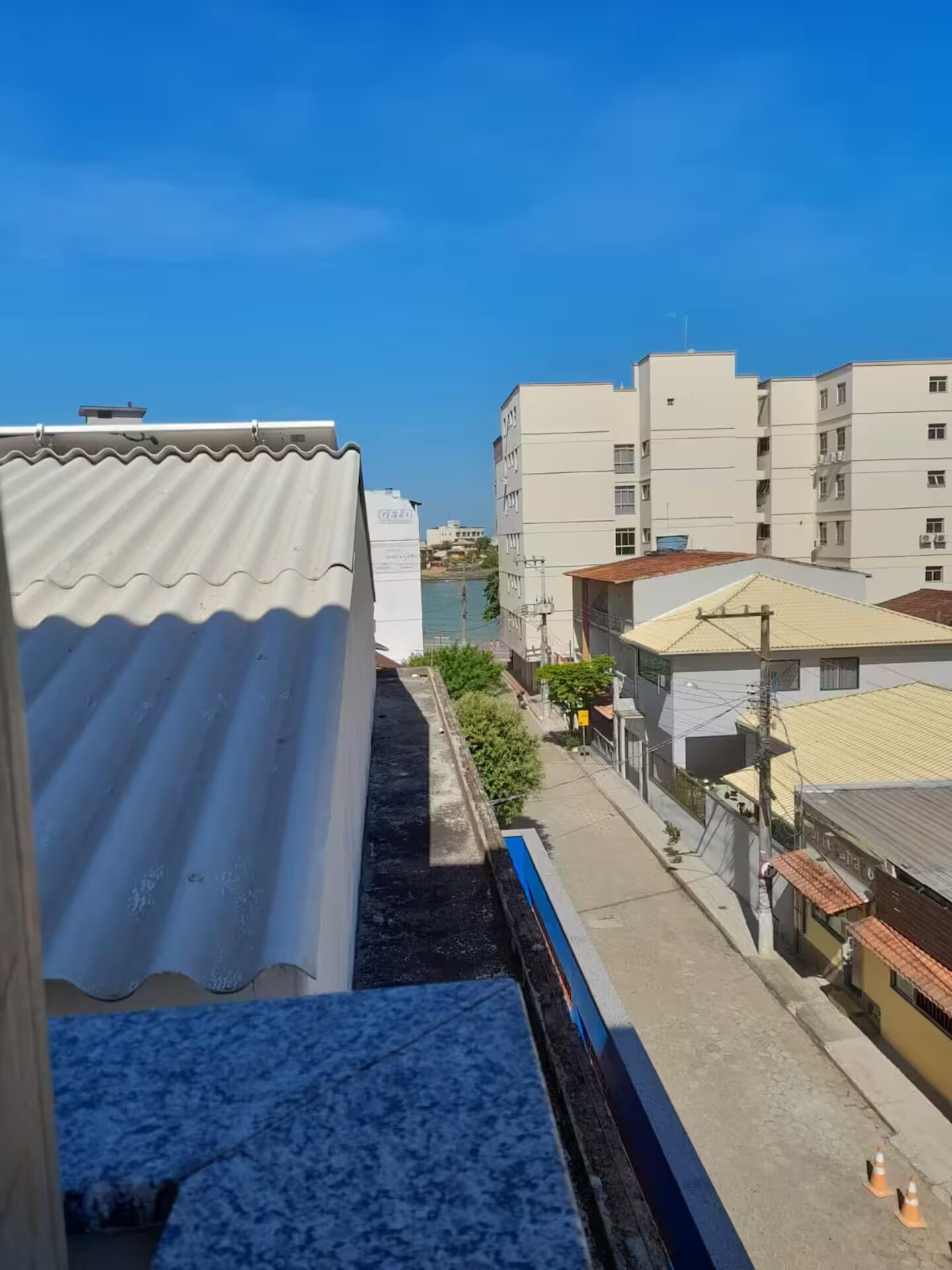 Un quartiere residenziale con edifici moderni, cielo sereno e un canale di drenaggio visibile.