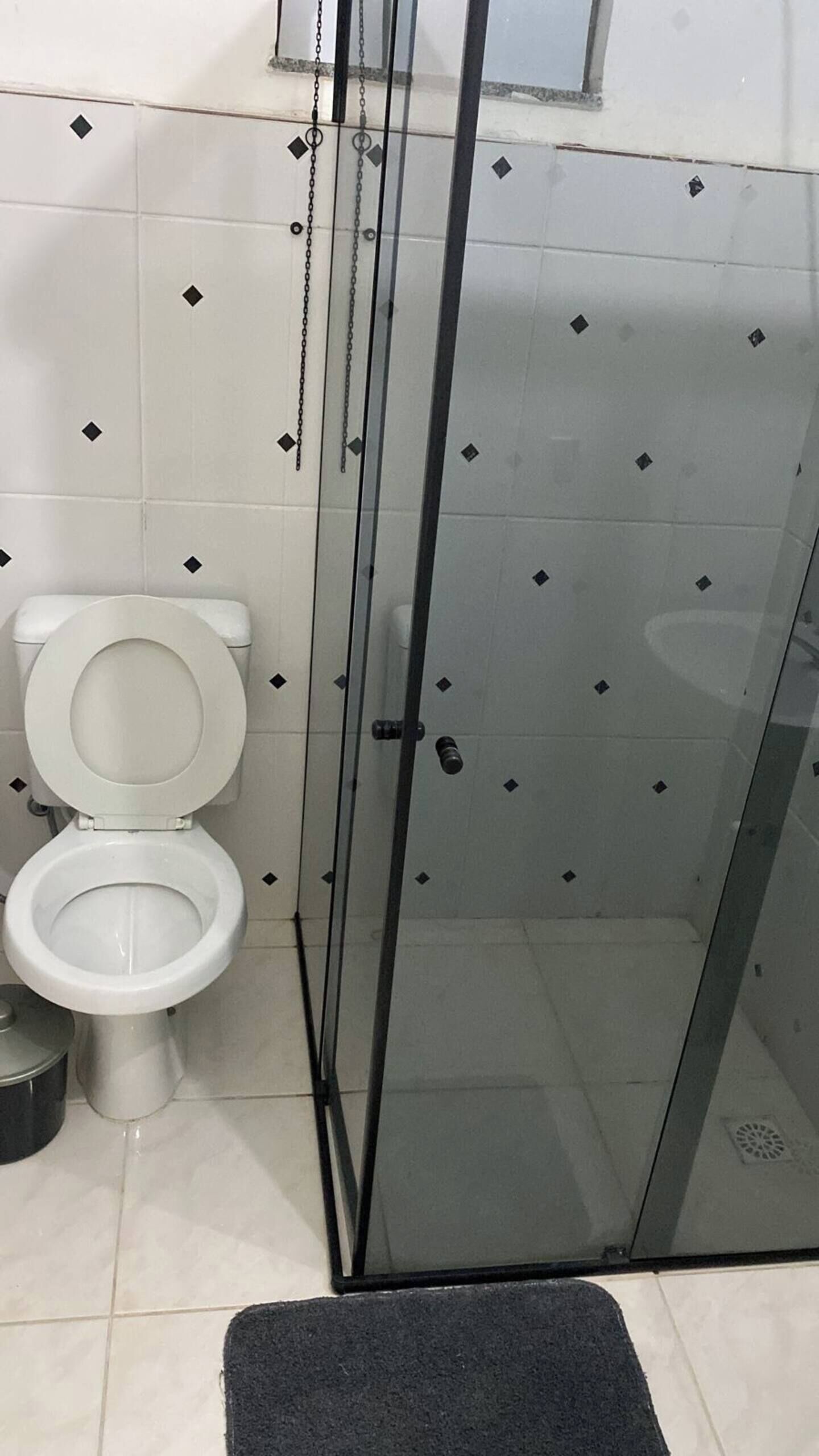 Une salle de bain comprenant des toilettes, un espace douche et des murs carrelés.