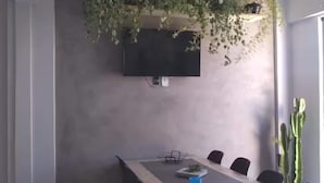 A conference room with a long table, chairs, a TV mounted on the wall, and potted plants. - Suite 303 beach walking distance (Anchieta)