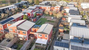 A residential area with multiple houses, some with solar panels, and a playground.