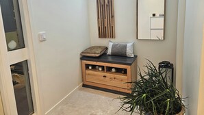 A hallway with a wooden cabinet, a mirror, and a potted plant.