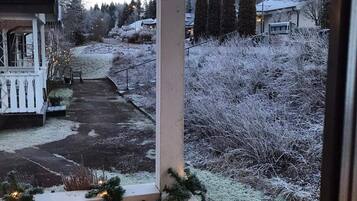 A porch with a view of a snowy landscape, including a gazebo and evergreen trees.