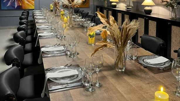 A long dining table set with chairs, candles, and decorative plants. - 7EVEN Suites (Lekki)