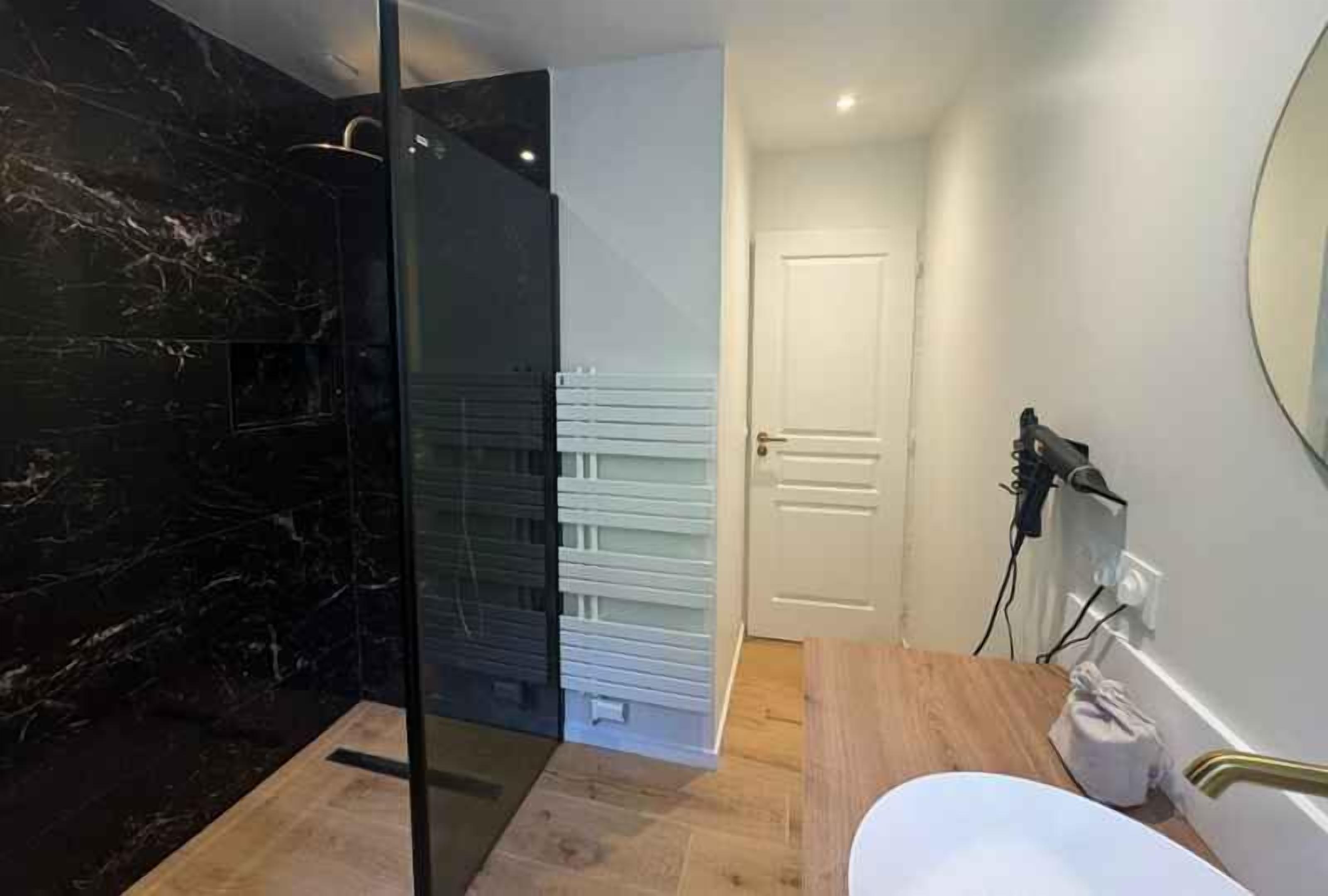 Une salle de bain moderne avec une douche à parois de verre, une porte blanche et un plancher en bois.