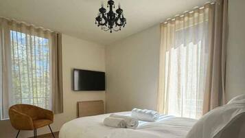 A hotel room with a bed, a chair, a television, and curtains.