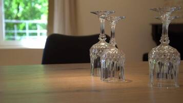 Three clear glass wine glasses on a wooden table with a window in the background.