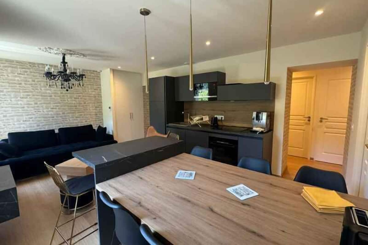A modern living space with a dining area, a kitchen, and a separate seating area.