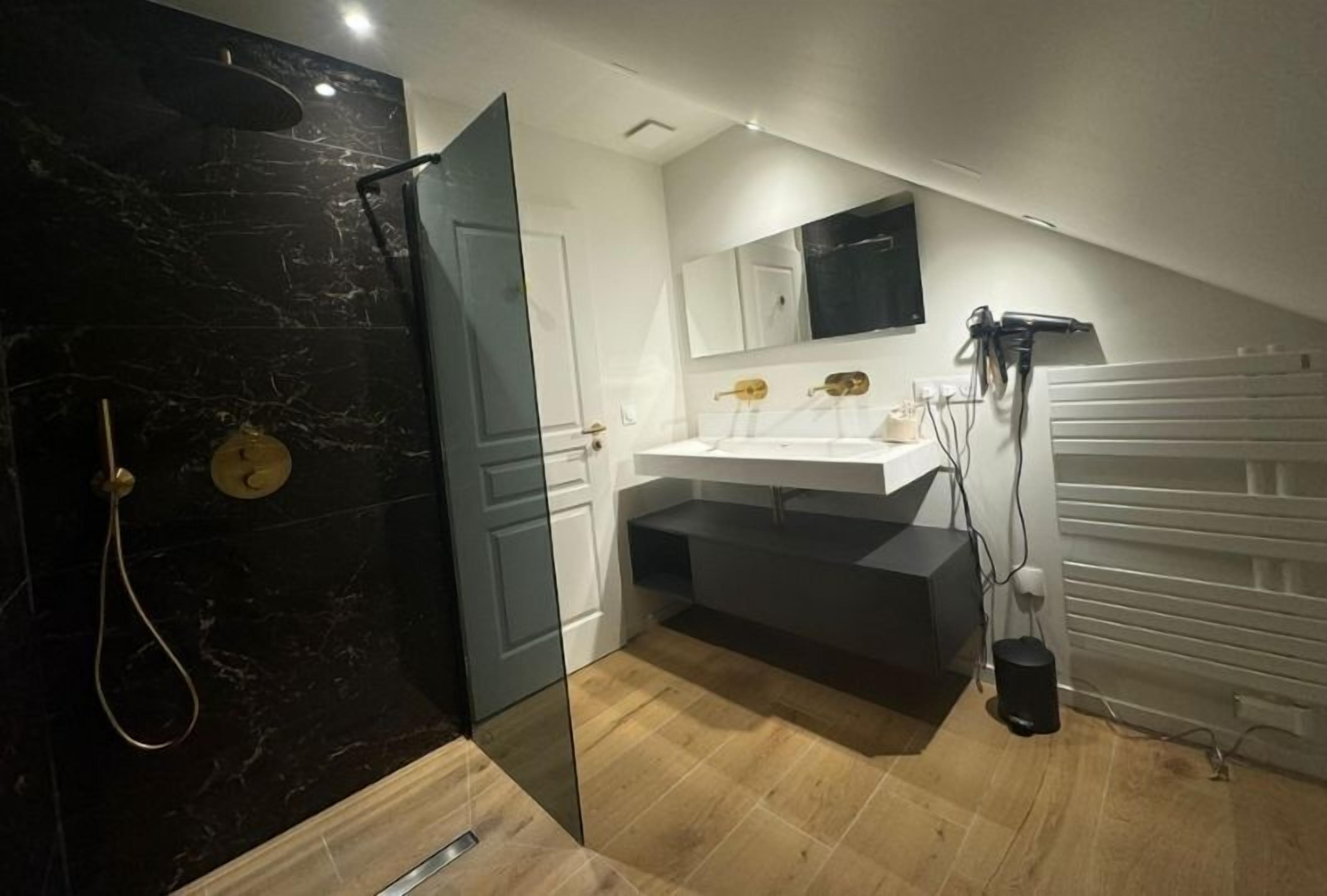 A modern bathroom with a glass shower enclosure, a white sink, and a vanity with a mirror.
