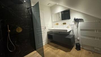 A modern bathroom with a glass shower enclosure, a white sink, and a vanity with a mirror.
