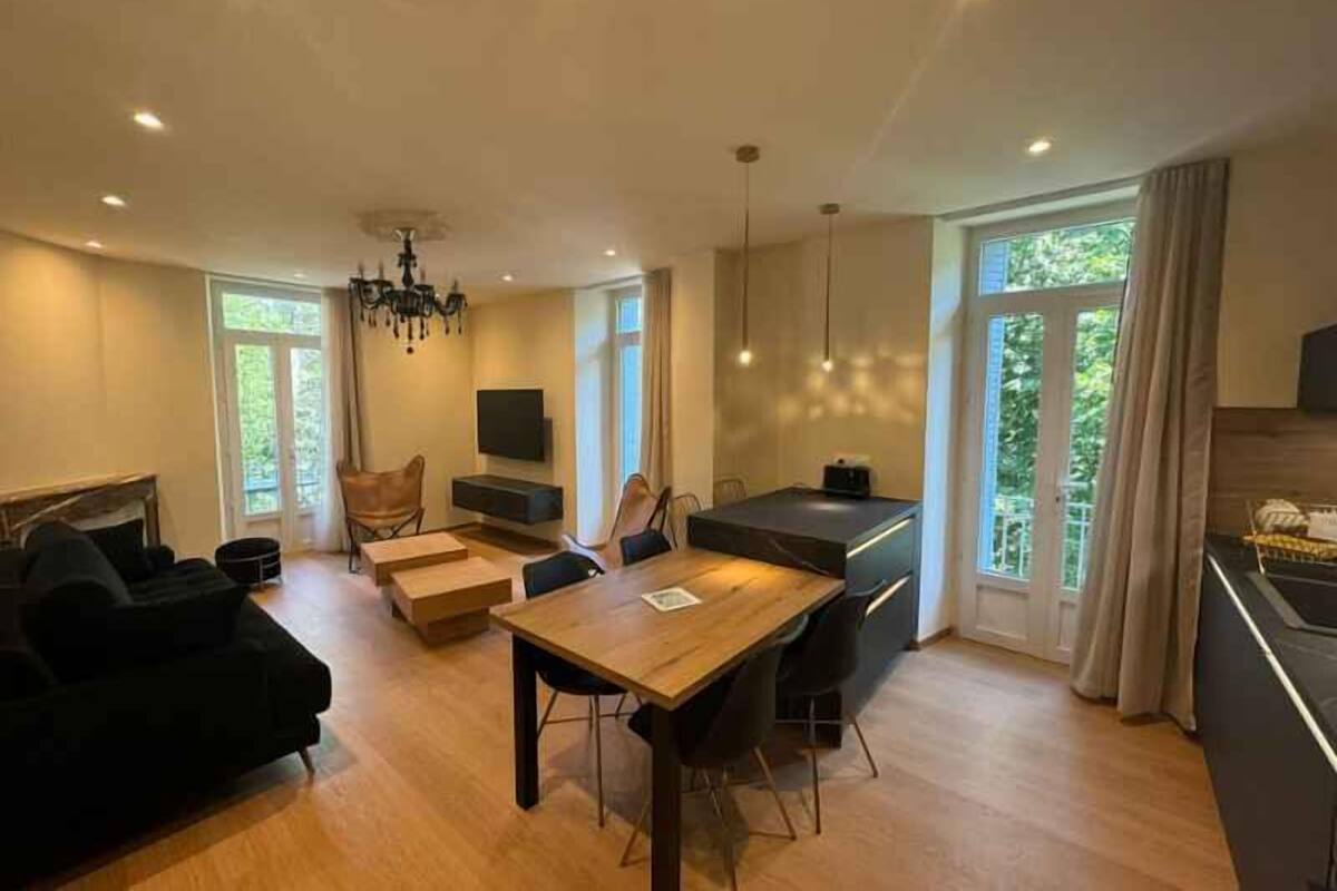 A modern living room with a dining area, a fireplace, and a kitchen.