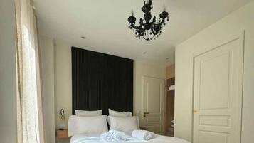 A hotel room with a bed, a chandelier, a wardrobe, and a door.